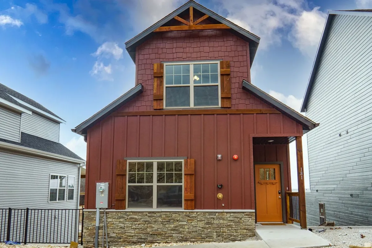 This image captures the impressive exterior of the property, featuring stone accents, large windows, and a welcoming front entrance. The spacious porch hints at the lifestyle of al fresco dining, sunset watching, and gatherings with friends and family.