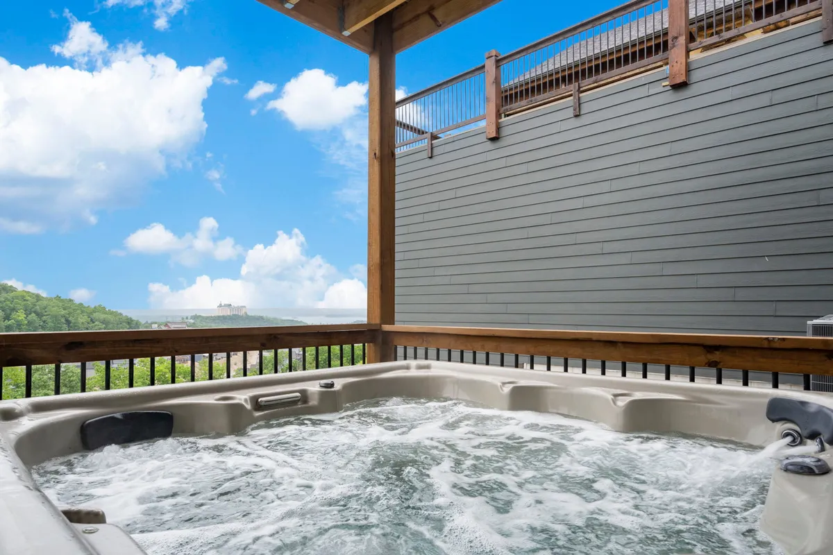 This exterior image showcases a bubbling hot tub positioned on a patio with sweeping views of the lake and a blue sky overhead. The inviting spa is clearly set up for relaxation, with ample space for small groups and a direct connection to the natural scenery.