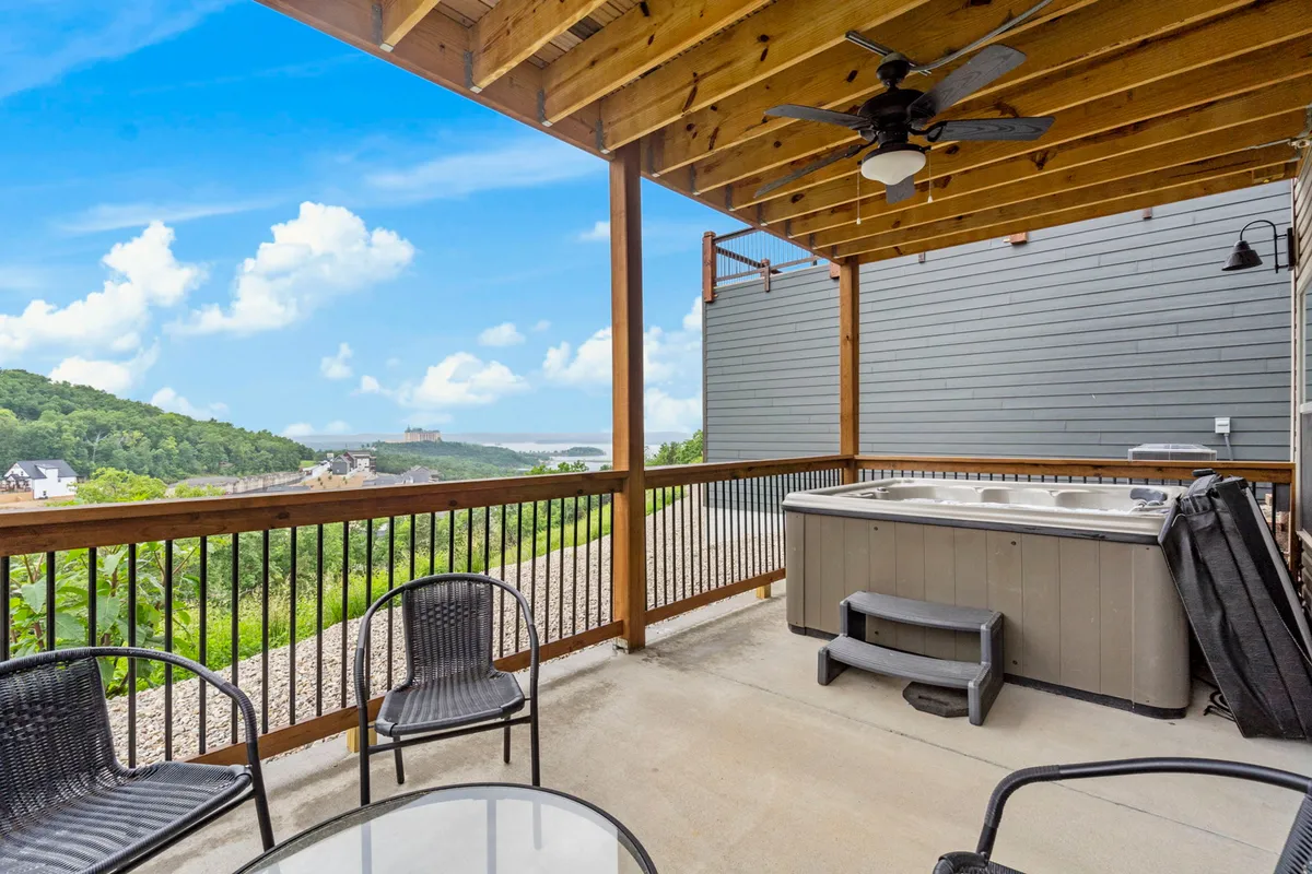 This image features an inviting outdoor hot tub and seating area overlooking a scenic natural landscape. The setting radiates tranquility with comfortable furnishings and unobstructed views, suggesting a perfect spot to unwind and enjoy the sunset or stargaze at night.